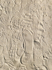 Variety of shoe footprints on beach sand