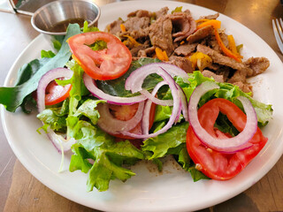 Sizzling beef fajitas paired with a colorful, crisp garden salad on a white plate