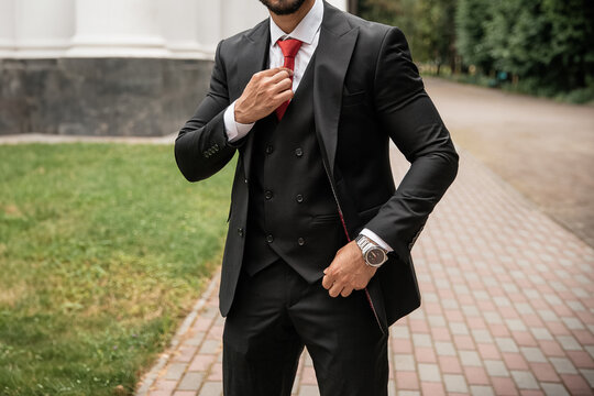 Stylish man in black luxury casual suit with red tie and expensive watch