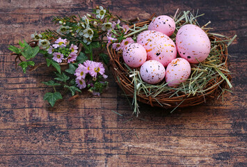 Nest mit rosa Ostereiern auf rustikalem Holz mit Platz für Text.
