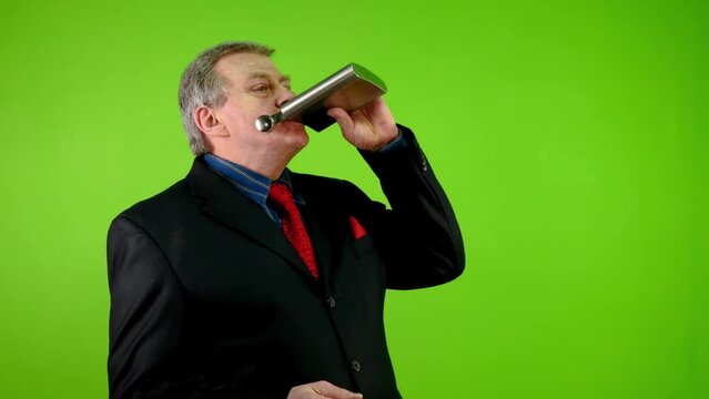 Businessman drinks alcohol from flask on working.