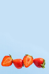Cut into pieces and whole strawberries in a row on a blue background, a copy of the space. Delicious and healthy food