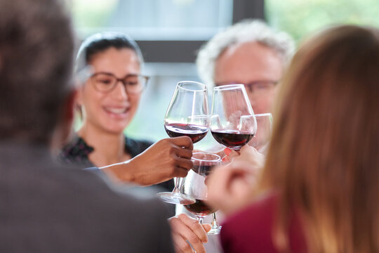 Business team clinking glasses of wine. Group of business people clinking wineglasses and proposing toast while celebrating finish of successful project in restaurant