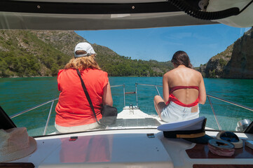 Dos mujeres toman el sol en la proa de una embarcación mientras navegan por un embalse en España.