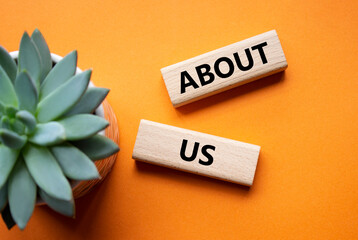 About us symbol. Concept word About us on wooden blocks. Beautiful orange background with succulent...