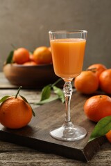 Delicious tangerine liqueur and fresh fruits on wooden table