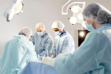 Group of doctors performing surgery in operating room - obrazy, fototapety, plakaty