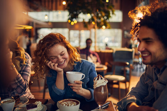 Young people at a cafe enjoying coffee and talking together