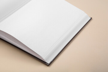 Open photo album on beige background, closeup. Space for text