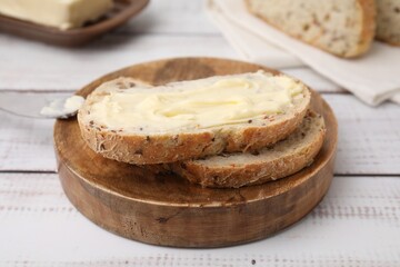 Slices of tasty bread with butter on white wooden table, closeup