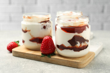 Tasty yoghurt with jam and strawberries on grey table, closeup