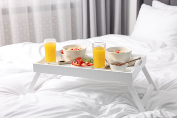 Tray with tasty breakfast on bed at home
