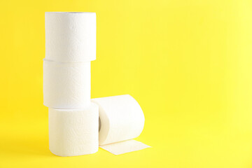 Many soft toilet paper rolls on yellow background. Space for text