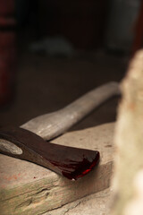 Axe with blood on wooden threshold, closeup