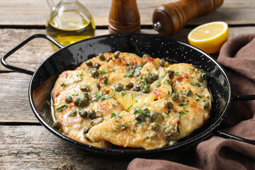 Delicious chicken piccata with herbs on wooden table