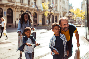 Happy family walking together on a city street with two children