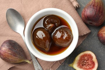Bowl of tasty sweet jam, fresh figs and spoon on grey table, flat lay