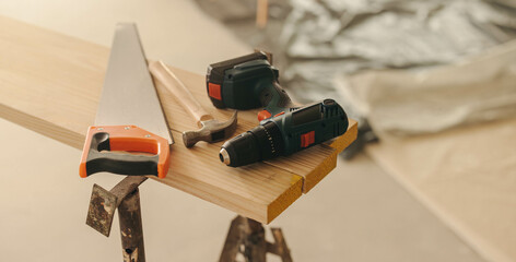 Home renovation tools for interior upgrade, including a hammer, drill gun, and crosscut saw