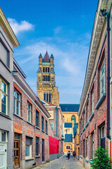 Bruges old town quarter, empty narrow cobblestone street in Brugge city historical centre, St. Salvator's Cathedral Roman Catholic church tower, vertical view, Flemish Region, Belgium