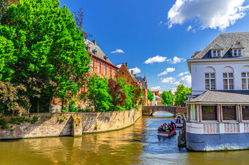 Fototapeta na wymiar Bruges cityscape, Stadhuis in Brugge old town scenic view, quarter historical city centre, river bank with green trees, bridge across Dijver water canal with motor boats, Flemish Region, Belgium