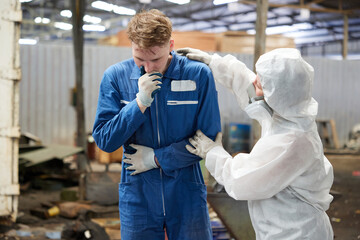 worker have a sick and coworker with personal protective equipment uniform(PPE) helping him in the...