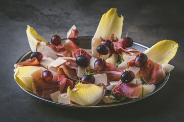 Sweet melon wrapped with ham, Italian appetizer, on gray rustic background