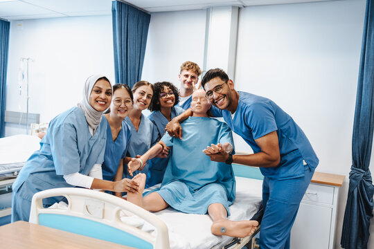 Diverse medical class posing with a patient simulator in a teaching hospital