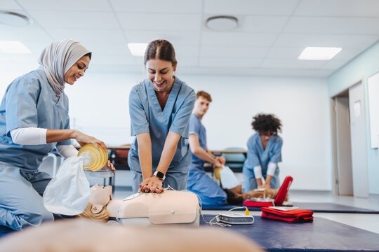 Happy nursing students perform CPR on a patient simulator