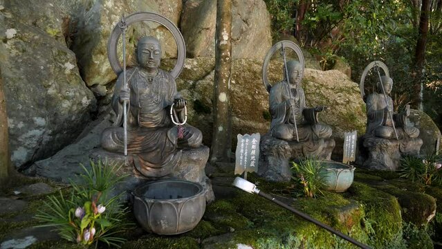 Rock Statues of buddha and bodhisattva in the nature Miyajima Island, Hiroshima, Japan. Traditional Japanese buddhist temple. Traditional Temples in Japan. Statues of guardian deity of children.