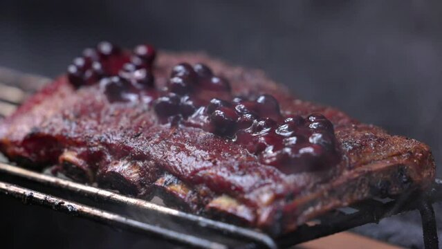 A rack of ribs with a sauce on top and smoke coming from it. The ribs are cooked and ready to be eaten