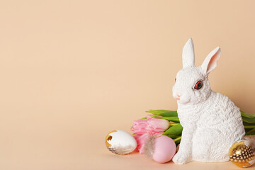 Happy Easter. Congratulatory beige Easter background with bunny, eggs and tulips, copy space