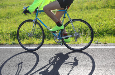 Fototapeta na wymiar young cyclist on racing bike on the street in backlight and shadow on asphalt