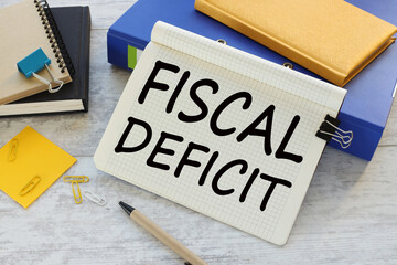FISCAL DEFICIT text on a notepad near a blue folder with a yellow notepad