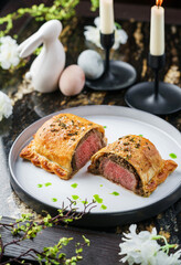 Fresh puff pastry bun with beef meat and spinach on marble table with easter decoration. Happy Easter food, top view