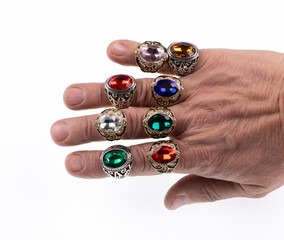 hand with a set of rings with colored stones isolated on white background