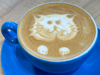 flat white. blue coffee cup. cat made from milk in a coffee-based drink. detail.