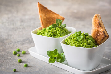 Pea puree with basil and roasted bread on rustic gray background, top view
