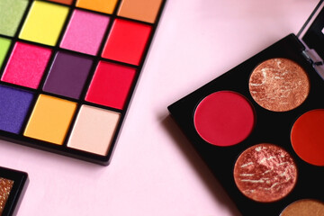 Various colorful eyeshadow palettes on bright pink background. Selective focus.