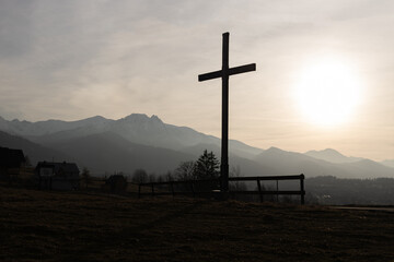 Religion theme, view of catholic cross silhouette, with fantastic sunset and mountains as...