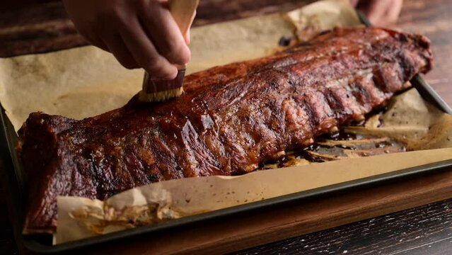 applying bbq sauce on pork spare ribs with brush