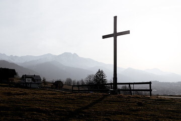 Religion theme, view of catholic cross silhouette, with fantastic sunset and mountains as background. Toned image - 750889911