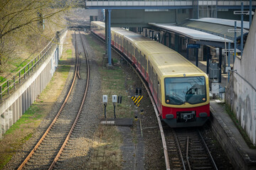 S bahn or suburban trains in Berlin, Germany. Modern red and yellow train for commuting purposes, on station of Messe Sud on a sunny spring day. Frontal view