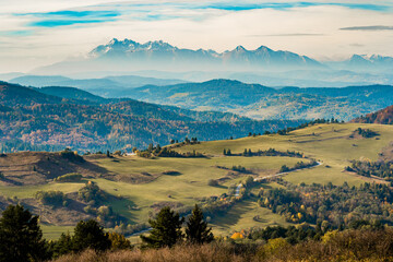 Mountain scenery with green pastures and rocky Tatra mountains in the background during the day.
