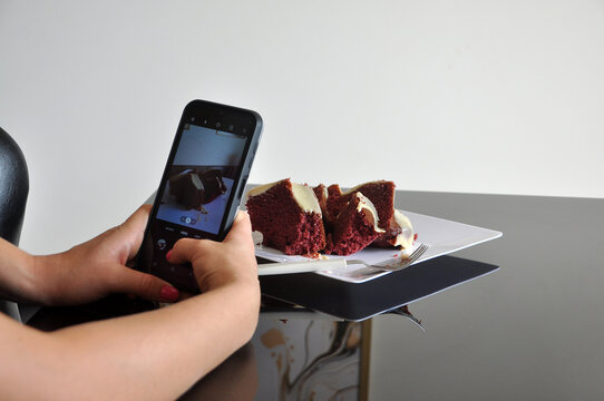 mãos de mulher tirando foto de bolo com  telefone celular 