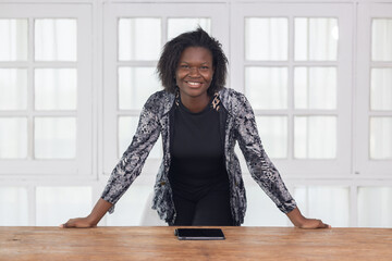 Black businesswoman in casual outfit standing in her office with hands on the table