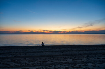 A teenage girl is meditating and exercising on the seashore watching a beautiful sunset. Sithonia, Greece, Halkidiki. Paradisos Beach in Neos Marmaras.
