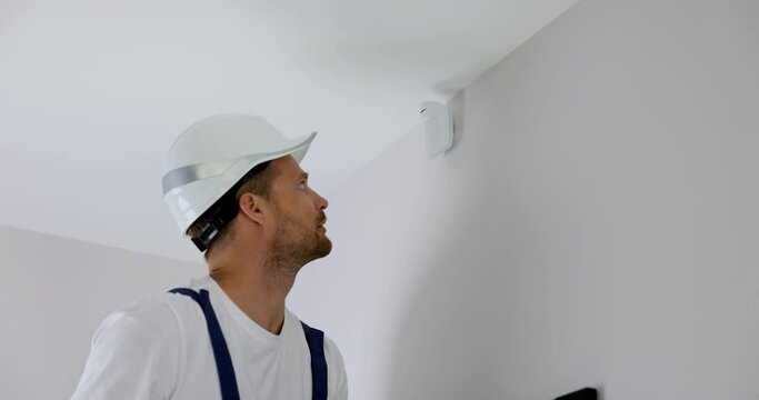 security system technician installing motion sensor on the wall at home