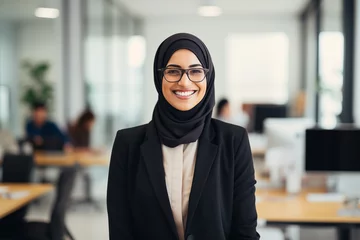 Fotobehang Portrait of smiling beautiful modern Muslim businesswoman in casual business suit and traditional hijab standing in the modern office. Confident Arabian lady. Equal women rights in Eastern countries. © okrasiuk