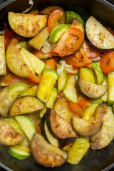 Vegetables fried in spices in a frying pan with spices close-up. Vertical