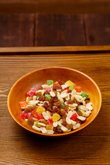 Mix of dried fruits and nuts on a wooden plate on the table. Vertical